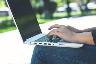 İş kadını bankta otururken dizüstü bilgisayarda çalışıyor.