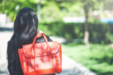 Kırmızı çantalı güzel bir kız parkta yürüyor.