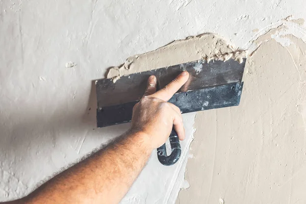 Hand with putty knife repair wall, Hand with a spatula, spatula with spackle paste structure, process of applying layer of putty trowel, working with spackling paste