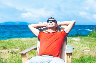 Nehir ve dağların yakınındaki güneş altında dinlenen genç adam..