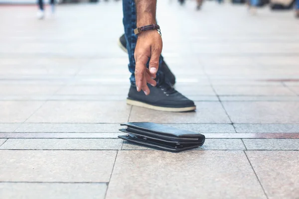 男子手皮夹在街上地板的背景 免版税图库图片