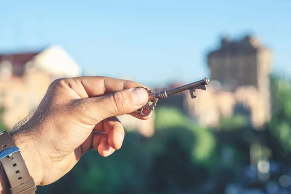 keys in hand, hand holds the keys to the apartment on the background of a new house. The concept of buying, selling, renting. Real estate agency, sale transaction.