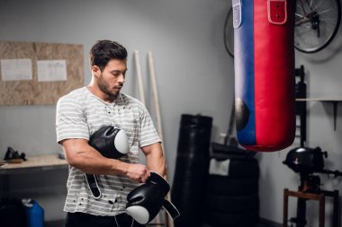 Genç bir boksör antrenmana hazırlanıyor, spor salonunda boks eldiveni giyiyor..