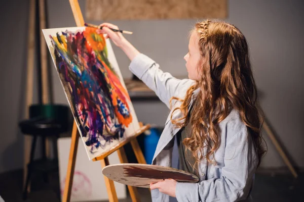 A little girl artist draws a picture with a brush in the Studio. A talented young schoolgirl — Stock Photo, Image