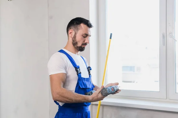 Repairman in overalls with a tape measure in his hands — Stock Photo, Image