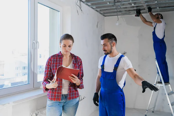 The woman checks the work of the builders in the apartment and writes a note — Stock Photo, Image