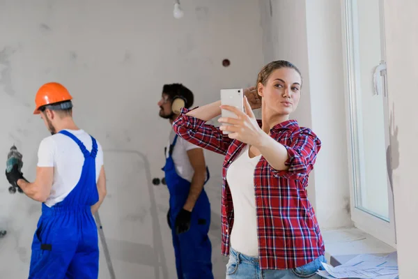 Cliente toma una selfie en el fondo de los constructores en el trabajo — Foto de Stock