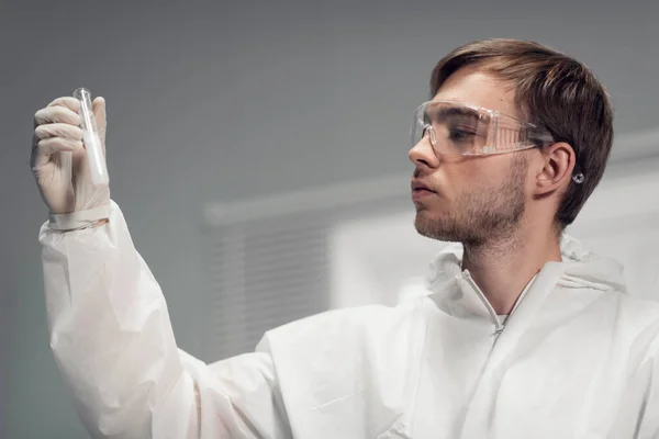 Retrato de close-up de um homem segurando um tubo de ensaio com líquido turvo branco, pesquisa próspera em um laboratório médico — Fotografia de Stock