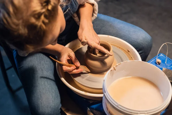 A young Potter girl in her Studio sculpts a pot with her hands and tools. — Stock Photo, Image