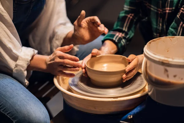 Крупным планом руки девушки-гончара и ребенка, которые делают глиняные тарелки на гончарном круге. — стоковое фото