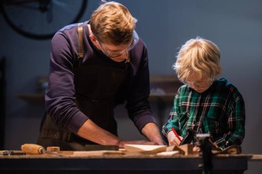 Kardeşler anneleri için garajda tahtadan bir hediye hazırlayın..