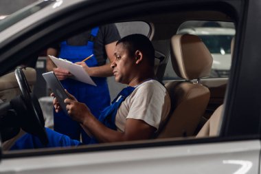 Arabanın ön koltuğunda oturan bir tamirci tablet kullanıyor.