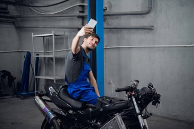 Bisikletin üzerinde otururken fotoğraf için poz veren bir zanaatkar.