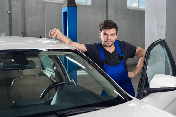 Üniformalı bir adam arabanın yanında duruyor.