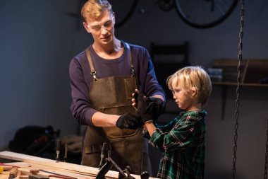 Kardeşler anneleri için garajda tahtadan bir hediye hazırlayın..