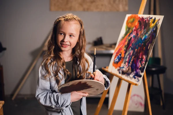 Jovencita artista creativa en el trabajo en un taller. Con pasión dibuja un cuadro inmerso en el trabajo. — Foto de Stock