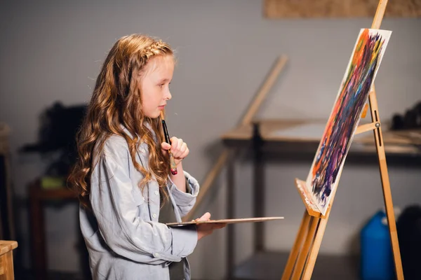 Young girl creative artist at work in a workshop. With passion draws a picture immersed in work. — Stock Photo, Image