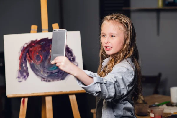 Una joven artista encantadora dirige una clase magistral en línea en el dibujo de imágenes en su taller. — Foto de Stock