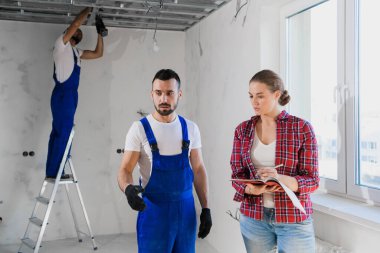 Müşteri üniformalı bir mimarla konuşur ve not defterine not alır.