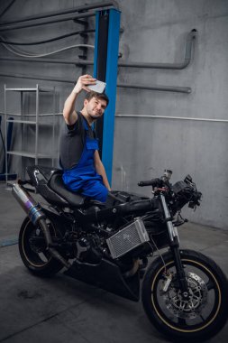 Tamirci motosikletle fotoğraf çeker.