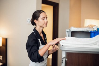 Genç üniformalı bir hizmetçi temiz havlu getiriyor.