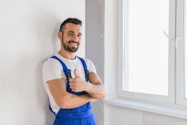 Tulumlu ustabaşı başparmağını gösteriyor ve gülümsüyor.