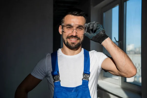 Reparatören i handskar och glasögon ler vänligt — Stockfoto