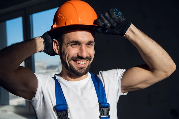 Trevlig reparatör i arbetskläder rätar ut orange hatt — Stockfoto