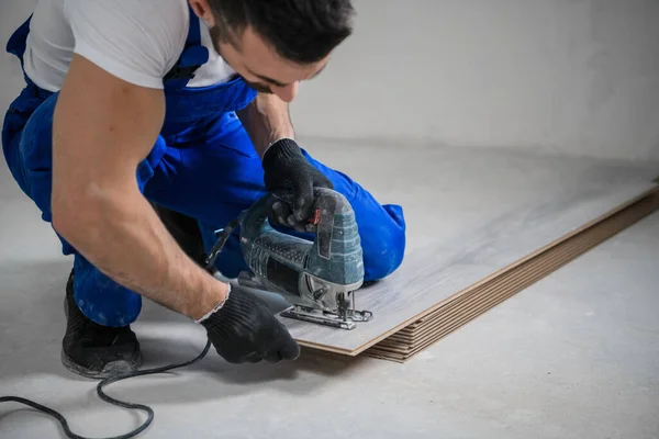 Handyman em azul uniforme corta laminado com quebra-cabeças — Fotografia de Stock