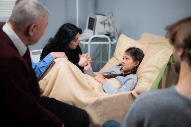 Hastane yatağında yatan kızını neşelendirmeye çalışan bir anne.