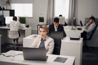 Ofiste çalışan genç bir kız yönetici dizüstü bilgisayarla şirketin bir müşterisiyle iletişim kuruyor..