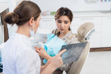 Bir doktor hastasına röntgen gösteriyor ve bazı şeyleri açıklıyor.