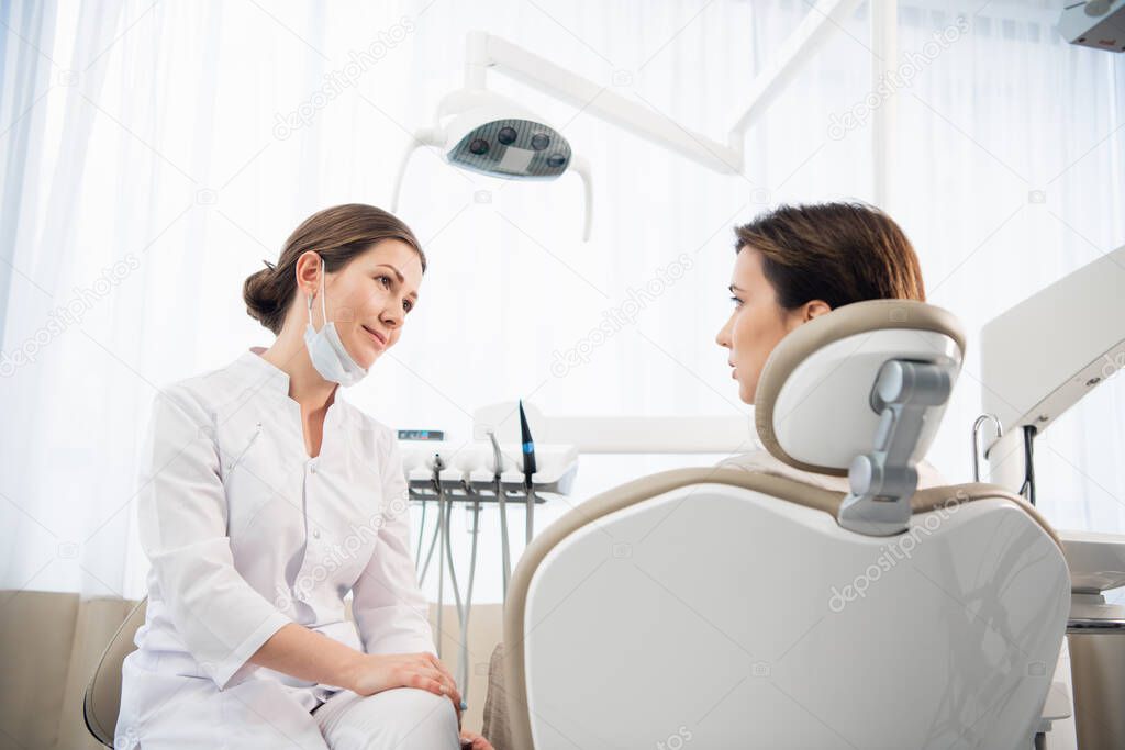 A young woman explaining her dental problem to her doctor, the d
