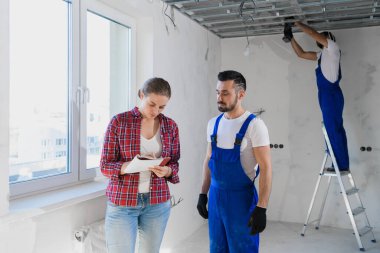 Tuğgeneral dairedeki tamircilerin işlerini kontrol eder ve bir not yazar.