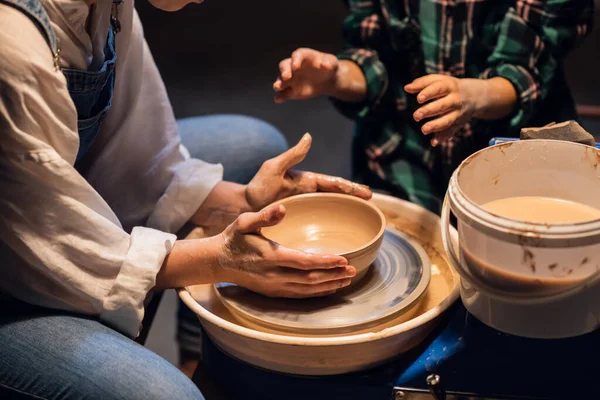 Урок керамики в художественной школе преподает молодая девушка гончар для милого ребенка. — стоковое фото