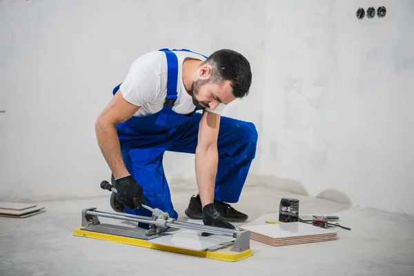 Bouwer in blauwe werkkleding maakt gebruik van een tegelsnijder — Stockfoto