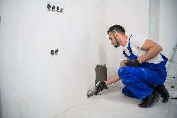 Een werknemer past cement toe op de muur om de tegels te bevestigen — Stockfoto