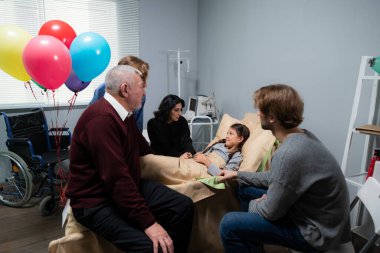 Kazadan sonra güzel, küçük bir kızı ziyarete gelen bir aile. Kız hastanede yatıyor. Tekerlekli sandalyesi köşede.