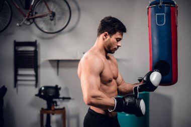 Deneyimli bir kas sporcusu dövüşe hazırlanır ve boks eldiveni giyer..