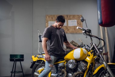 Vahşi bir motorcu sarı güçlü bir motosiklet satın alır. Garajda kontrol ediyor..