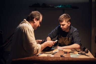 Yaşlı bir kunduracı ve çırağı atölyelerinde çeşitli aletlerle el yapımı ayakkabılar yapıyorlar..