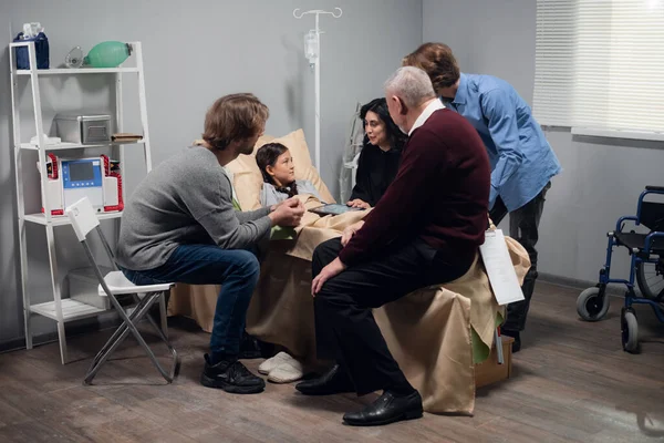 Hastane koğuşunda yatmakta olan güzel, küçük bir kızı ziyaret eden bir aile.