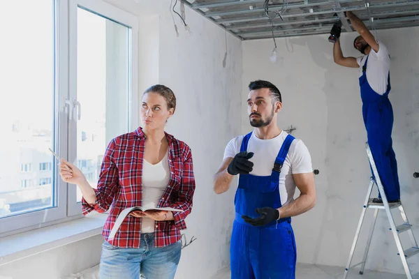 Der Vorgesetzte überprüft die Arbeit der Bauarbeiter in der Wohnung und schreibt eine Notiz — Stockfoto