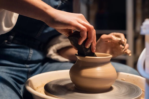 A Potter girl sculpts a pot on a Potters wheel with her hands and tools. — Stock Photo, Image