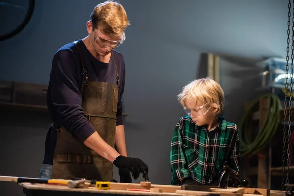 Deneyimli bir marangoz ve genç çırağı atölyelerinde ahşap işçiliği yapıyorlar..