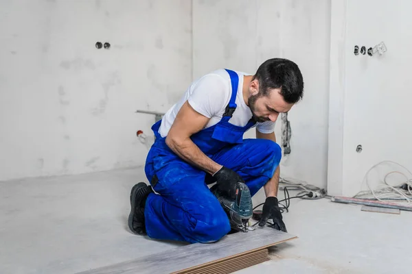 Skäggig förman sågar en träskiva med en pussel — Stockfoto