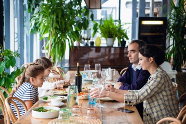 Gülümseyen aile mutfakta birlikte yemek yiyor.