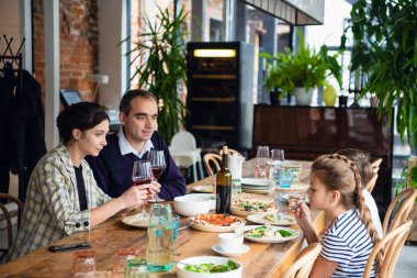 Gülümseyen aile mutfakta birlikte yemek yiyor.