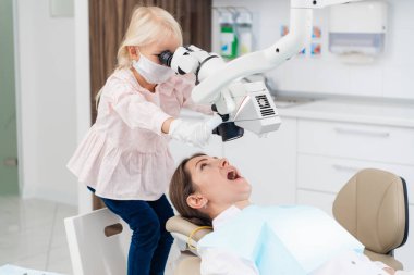 Klinikteki çocuk, küçük doktor, dişçilik oynayan küçük bir doktor maske ve silikon eldiven takıyor.