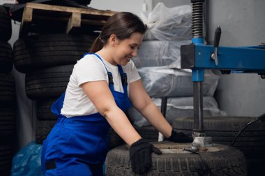 Atölye çalışanı pres kullanarak araba tekerleğini tamir ediyor.